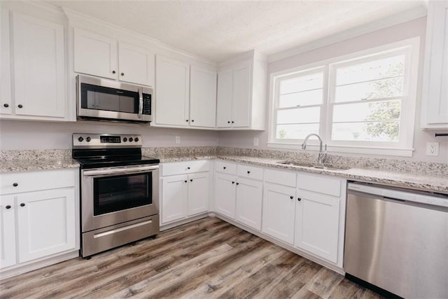 1233 Bethlehem Rd, Statham, GA 30666 - kitchen with appliances with stainless steel finishes, a sink, white cabinets, light wood-style flooring, and a textured ceiling