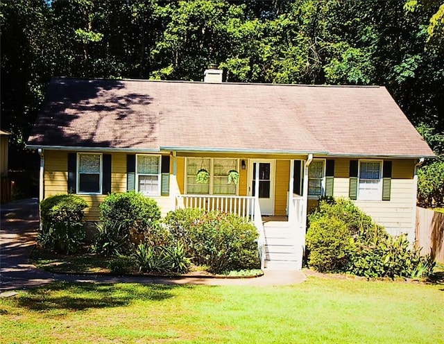 single story home with a chimney, covered porch, and a front lawn