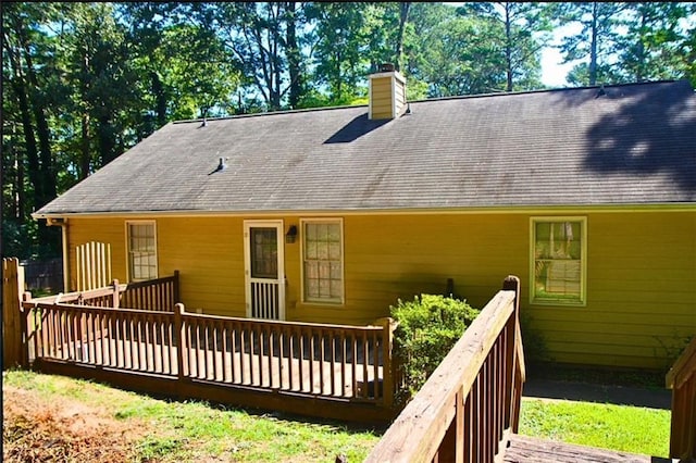 rear view of property featuring a chimney and a deck