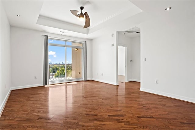 spare room featuring a ceiling fan, wood finished floors, baseboards, ornamental molding, and a raised ceiling