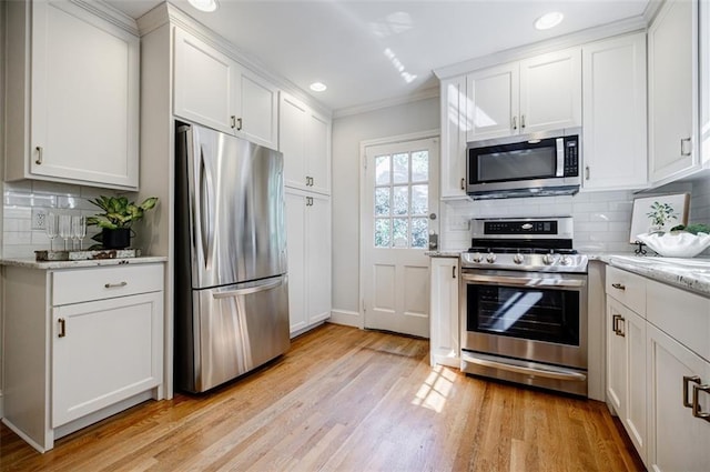2007 Mount Vernon Pl, Dunwoody, GA 30338 - kitchen featuring appliances with stainless steel finishes, light wood-style flooring, white cabinets, decorative backsplash, and crown molding