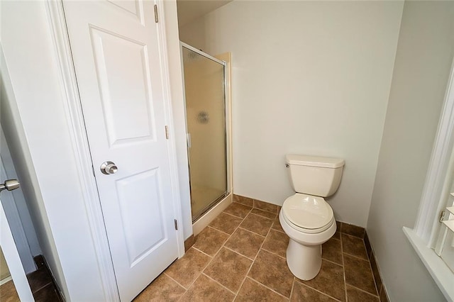 bathroom featuring tile patterned floors, baseboards, toilet, and a shower stall