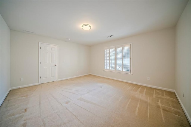 spare room with light carpet, visible vents, and baseboards