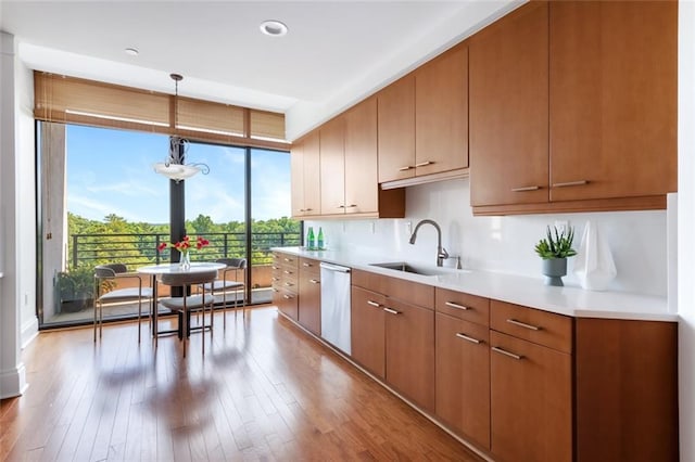 kitchen featuring decorative light fixtures, dishwasher, sink, floor to ceiling windows, and light hardwood / wood-style flooring