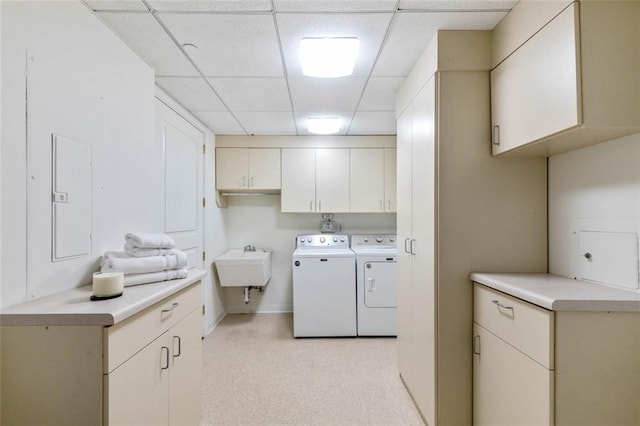 clothes washing area with sink, washing machine and dryer, cabinets, and electric panel