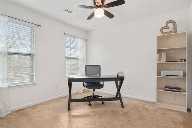 office with a textured ceiling, ceiling fan, visible vents, baseboards, and carpet