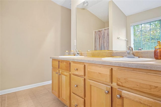 full bath with lofted ceiling, a sink, baseboards, and double vanity