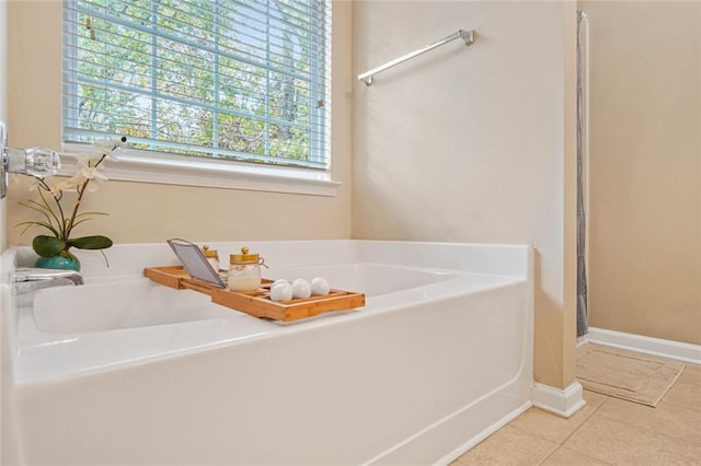 bathroom featuring baseboards, plenty of natural light, a bath, and tile patterned floors