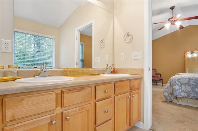 ensuite bathroom with ensuite bathroom, ceiling fan, vaulted ceiling, and a sink