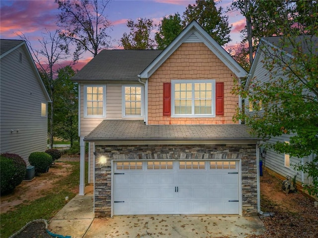 traditional home featuring an attached garage, stone siding, and a shingled roof