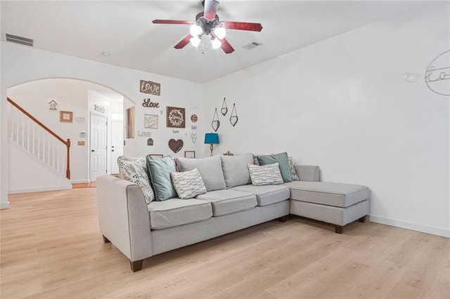 living room with light wood-style floors, visible vents, and arched walkways