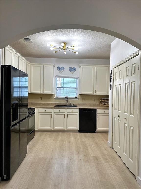 kitchen with arched walkways, black appliances, a sink, and white cabinets