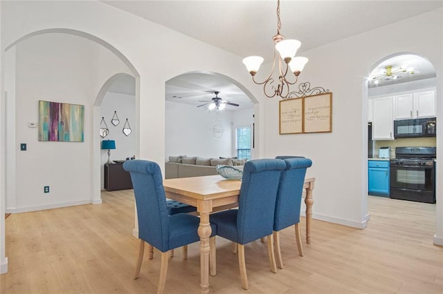 dining area with light wood-style floors, baseboards, arched walkways, and ceiling fan with notable chandelier