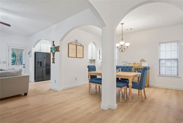 dining area featuring baseboards, a textured ceiling, light wood finished floors, and an inviting chandelier