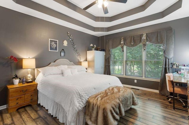 bedroom with dark hardwood / wood-style floors, a raised ceiling, and ceiling fan