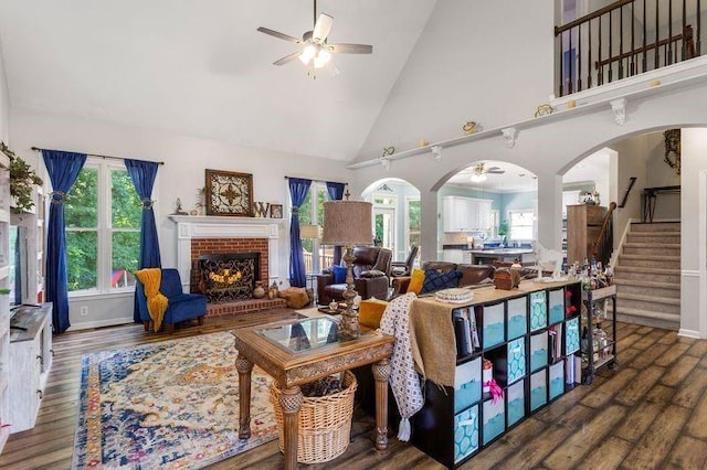 living room featuring dark hardwood / wood-style flooring, ceiling fan, a fireplace, and high vaulted ceiling