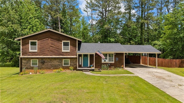 split level home featuring concrete driveway, a carport, brick siding, and view of wooded area