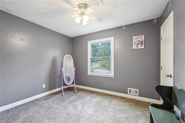 unfurnished room with carpet floors, a ceiling fan, baseboards, and a textured ceiling