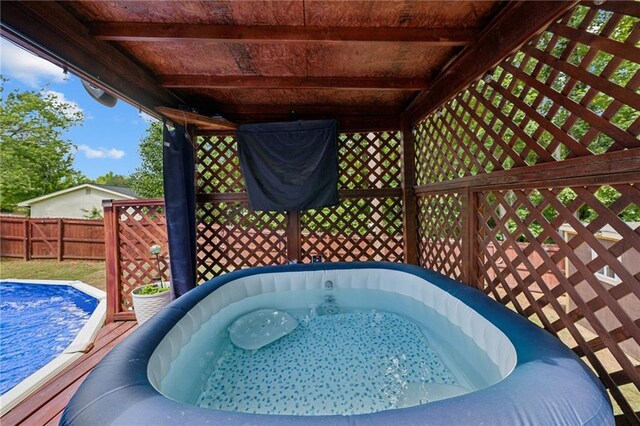 view of pool featuring fence and a jacuzzi