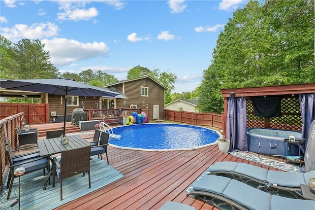 view of swimming pool with a wooden deck, a fenced backyard, and outdoor dining area
