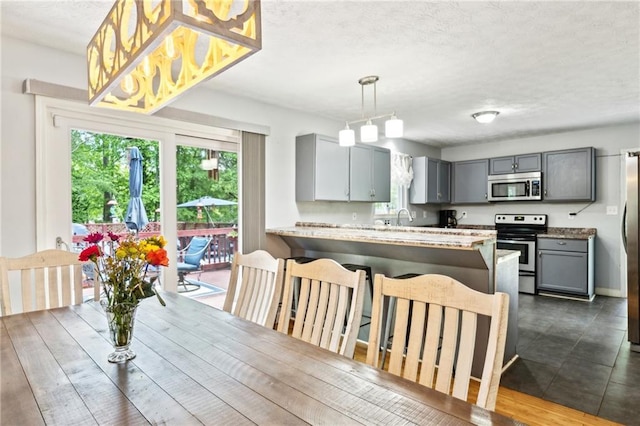 kitchen with appliances with stainless steel finishes, gray cabinets, a textured ceiling, a peninsula, and light countertops