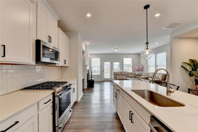 kitchen featuring pendant lighting, tasteful backsplash, white cabinetry, sink, and stainless steel appliances