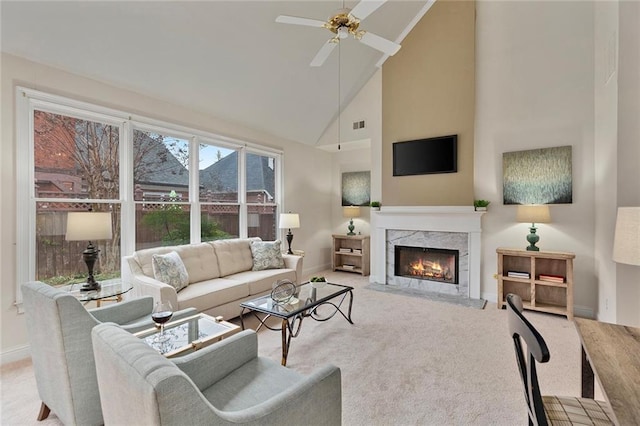 carpeted living area with baseboards, visible vents, a ceiling fan, high vaulted ceiling, and a high end fireplace