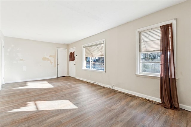 empty room with plenty of natural light and hardwood / wood-style floors