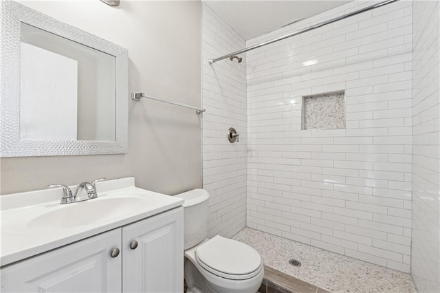 bathroom featuring vanity, tiled shower, and toilet