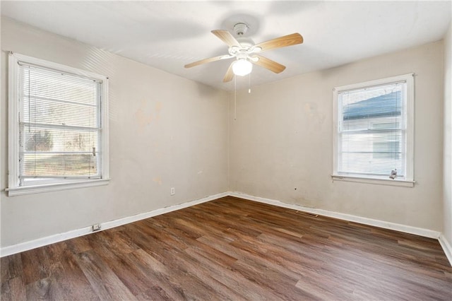 empty room with ceiling fan, plenty of natural light, and dark hardwood / wood-style flooring