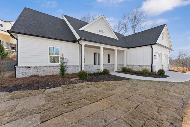 view of front of property featuring concrete driveway, brick siding, roof with shingles, and a porch