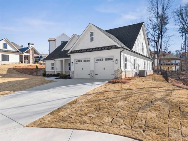 view of front facade with metal roof, central AC unit, an attached garage, driveway, and a standing seam roof