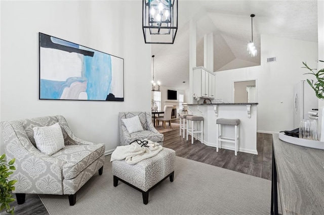 living room featuring dark hardwood / wood-style flooring, a chandelier, and high vaulted ceiling