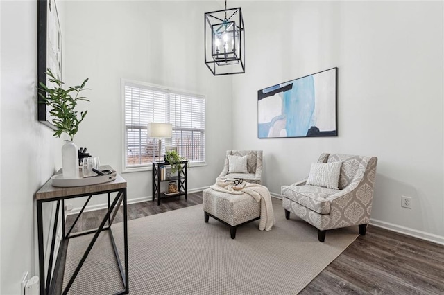 living area with an inviting chandelier, a towering ceiling, and dark wood-type flooring