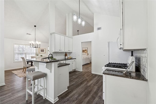 kitchen with pendant lighting, a kitchen bar, an inviting chandelier, and white cabinets