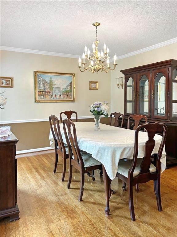 21 Picketts Ridge Ln, Acworth, GA 30101 - dining space with light wood-style floors, ornamental molding, a textured ceiling, and a chandelier