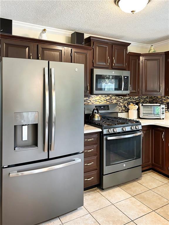 21 Picketts Ridge Ln, Acworth, GA 30101 - kitchen featuring appliances with stainless steel finishes, light countertops, dark brown cabinetry, light tile patterned floors, and a textured ceiling