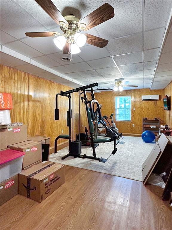 21 Picketts Ridge Ln, Acworth, GA 30101 - exercise area featuring a ceiling fan, a drop ceiling, wood finished floors, wooden walls, and a wall unit AC