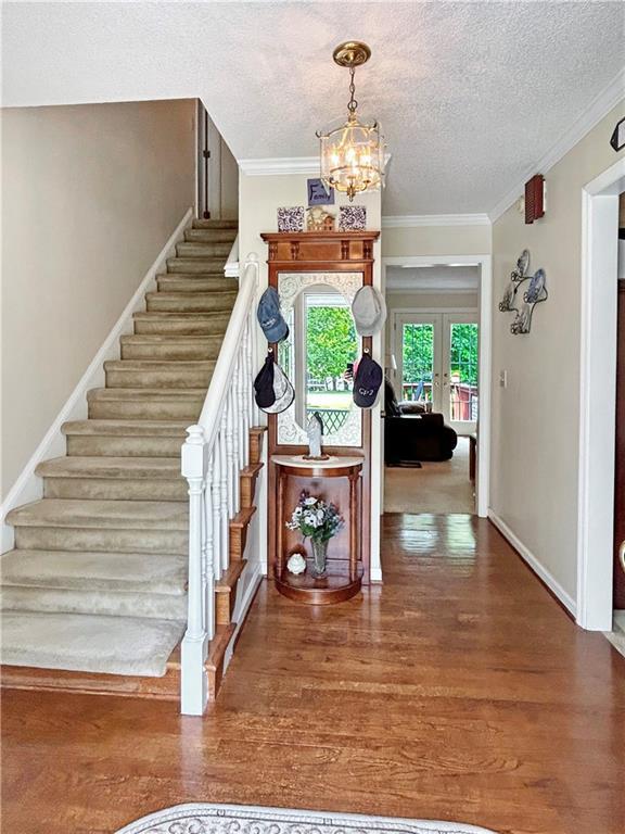 21 Picketts Ridge Ln, Acworth, GA 30101 - foyer entrance featuring stairs, a chandelier, wood finished floors, a textured ceiling, and crown molding