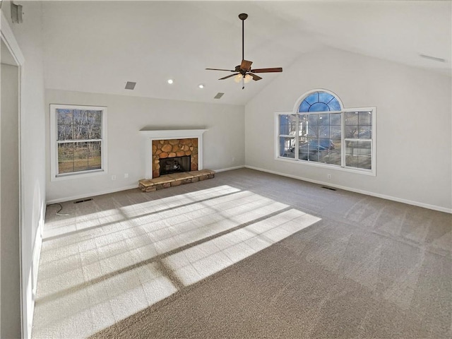 unfurnished living room featuring carpet, lofted ceiling, visible vents, a stone fireplace, and baseboards