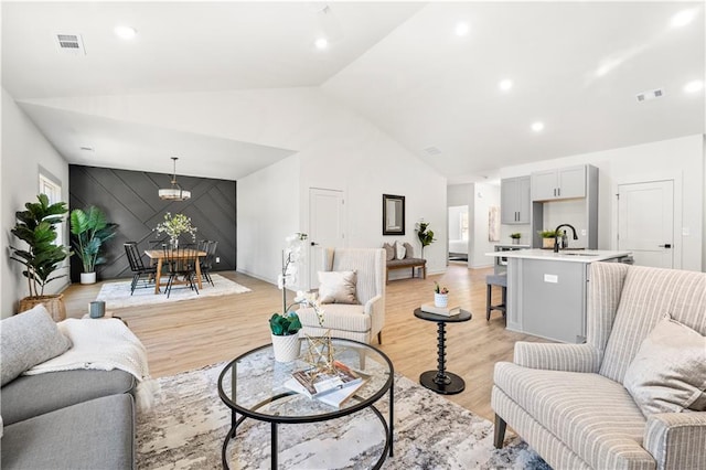 living room featuring sink, light hardwood / wood-style floors, and lofted ceiling