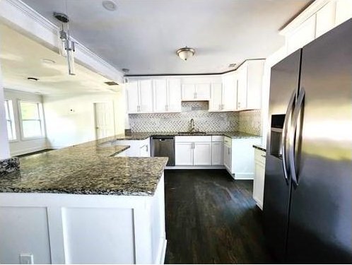 kitchen with stainless steel fridge, dark stone countertops, tasteful backsplash, decorative light fixtures, and sink