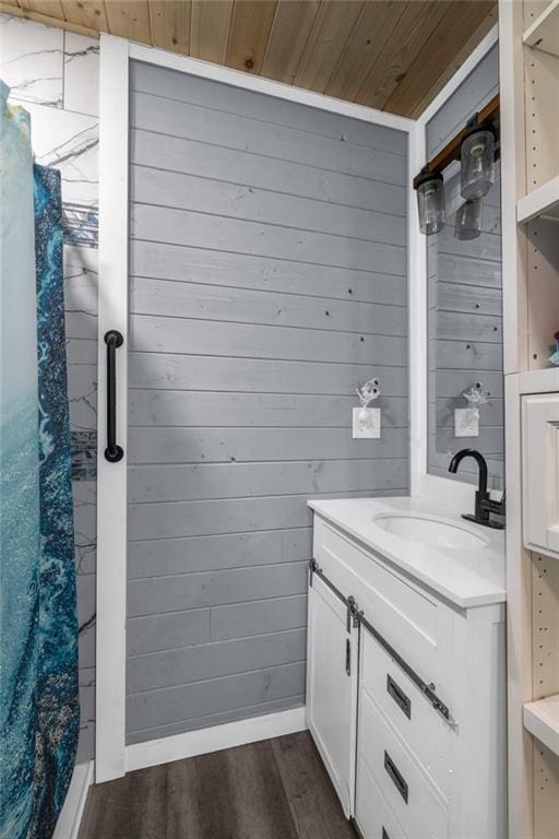 bathroom featuring wooden walls, wooden ceiling, vanity, and wood finished floors