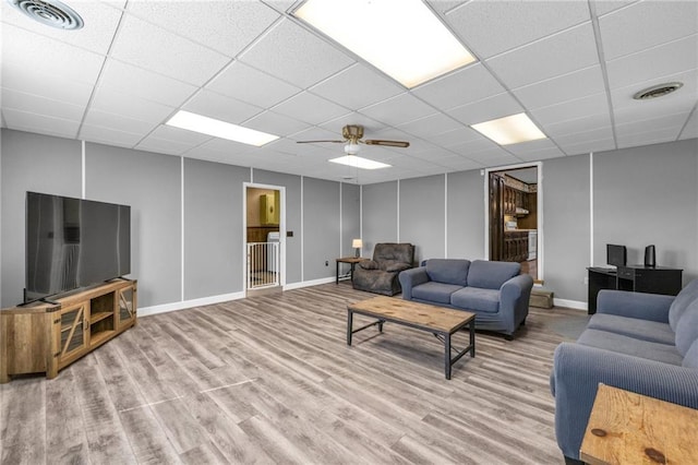 living area featuring a drop ceiling, visible vents, baseboards, and light wood-style floors