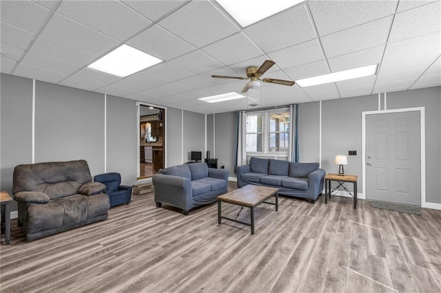 living area with wood finished floors, baseboards, and a paneled ceiling