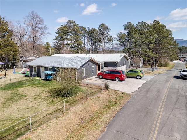 single story home with driveway, metal roof, a front lawn, and fence