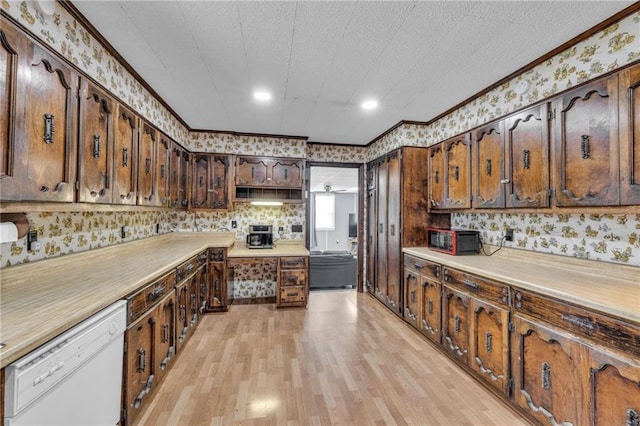 kitchen featuring dishwasher, ornamental molding, light countertops, and wallpapered walls