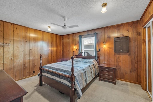 bedroom with baseboards, light colored carpet, a textured ceiling, and ceiling fan