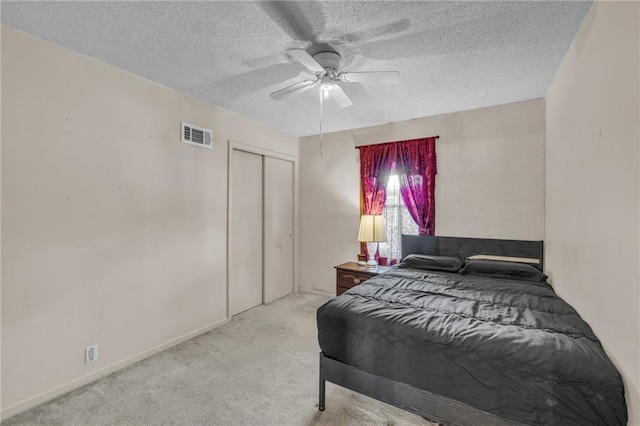 carpeted bedroom with visible vents, a textured ceiling, a closet, and ceiling fan