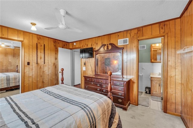 bedroom featuring visible vents, light colored carpet, a textured ceiling, and wooden walls